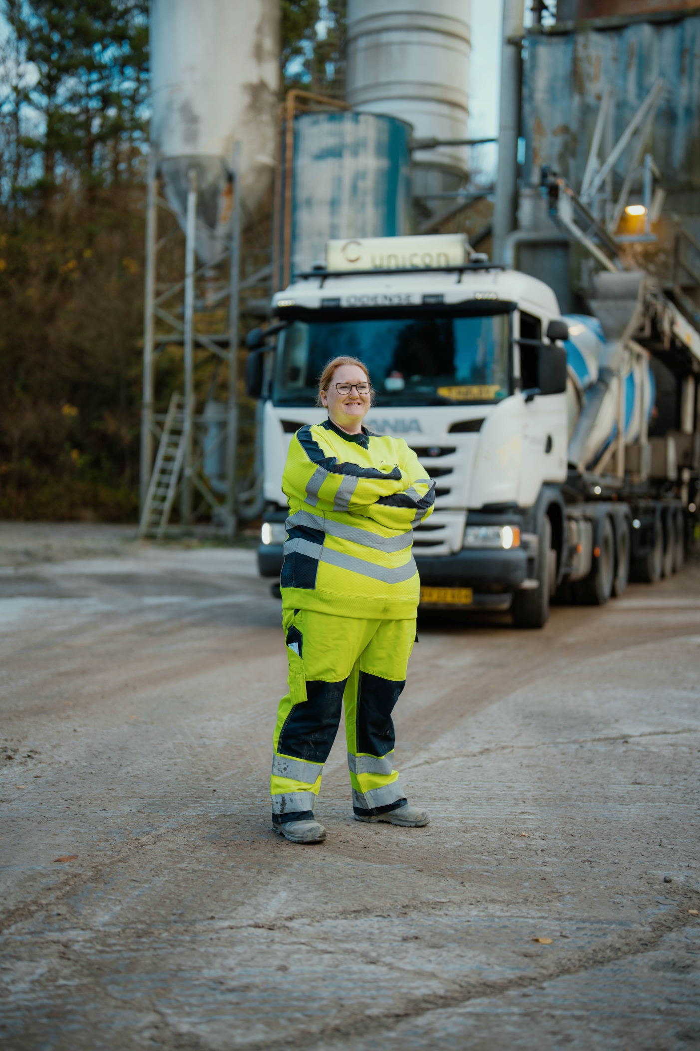 Smilende betonchauffør står foran sin Unicon-betonbil ved betonværket.