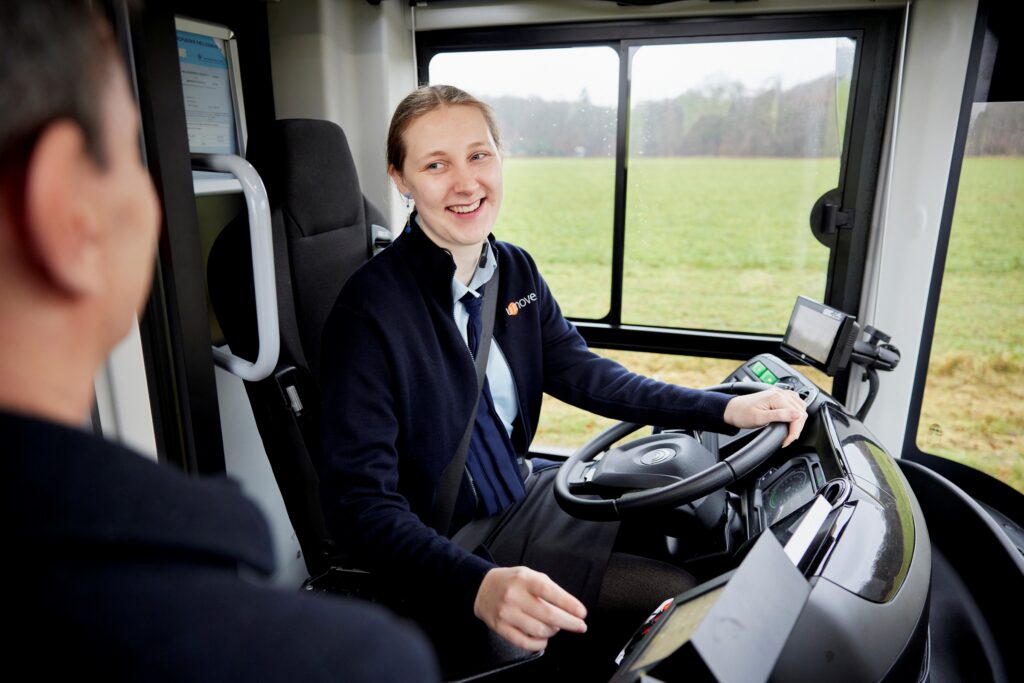 Smilende buschauffør fra Umove i samtale med passager fra førersædet.