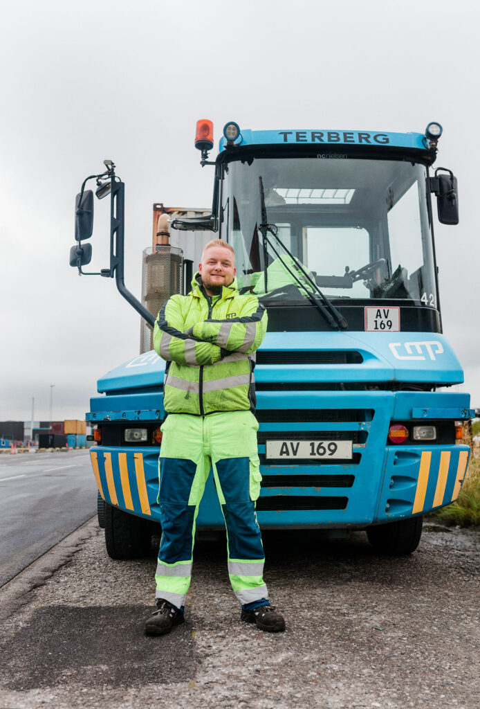 Terminalchauffør står foran sin blå Terberg-terminaltraktor på Copenhagen Malmö Port.