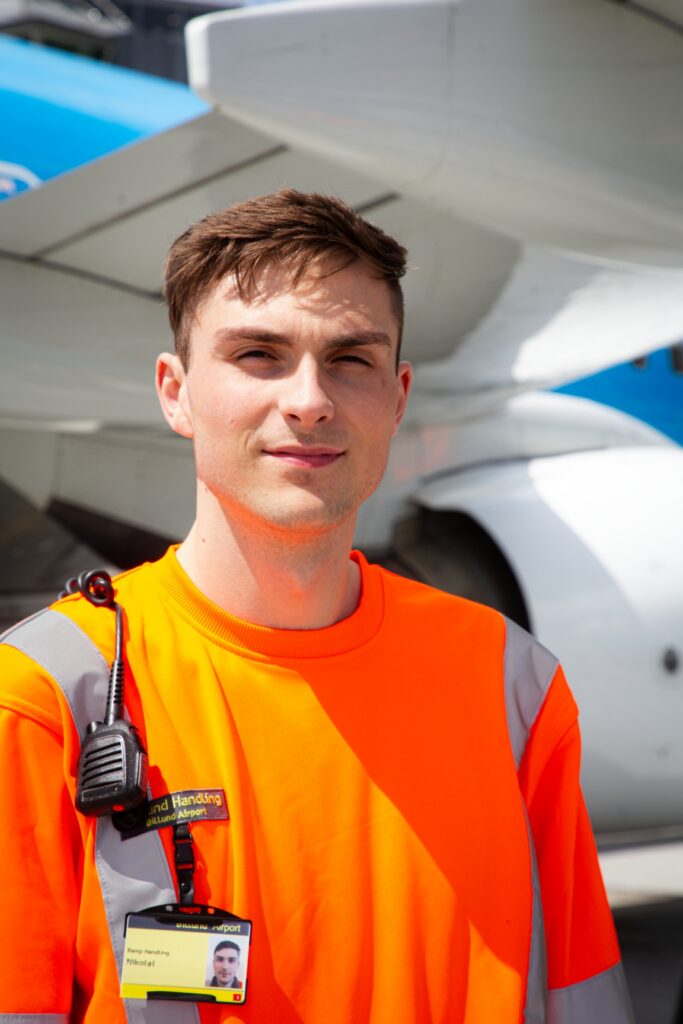 Portræt af ung lufthavnsoperatør i Billund Lufthavn foran flymotor.